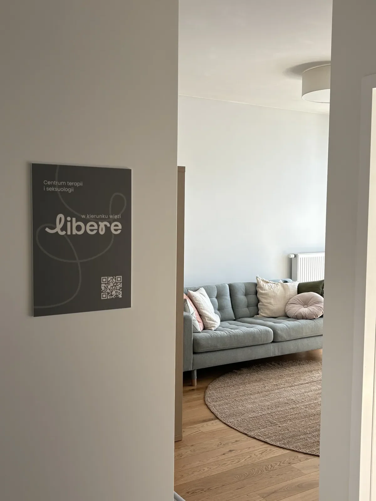 Widok z korytarza do gabinetu w Oliwie, kanapa i tabliczka centrum